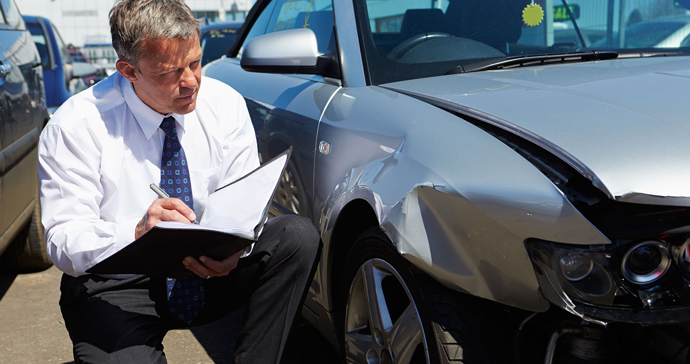 Auto insurance agent besides crashed car hood