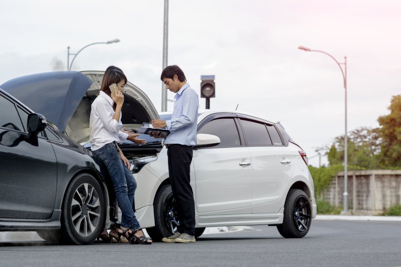 Woman driver calls for instruction during insurance agent review the dammage of the car after accident