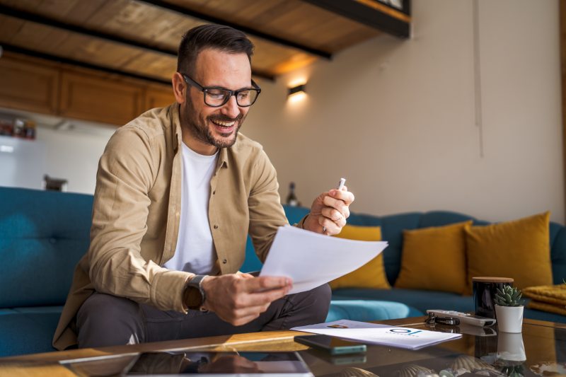 One man mature caucasian male work at home hold paper document sign insurance contract or read report enjoy good news in letter receive official paper about tax refund credit loan approval