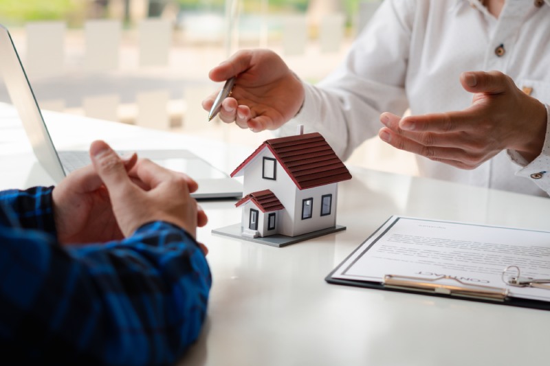 The real estate agent is explaining the house style to the clients who come to contact to see the house design and the purchase agreement. Within a modern office