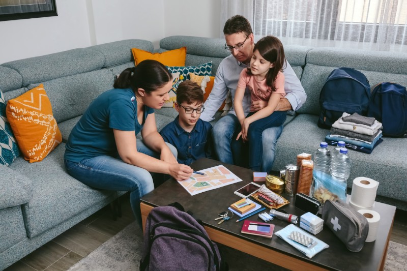 Mother explaining to her family the assembly point map while preparing emergency backpacks