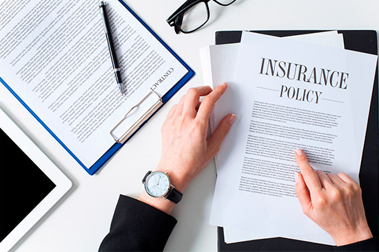 An insurance policy placed on a desk with a laptop and tablet, focusing on hurricane season strategies for small businesses.