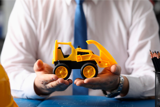 A man holds a toy construction vehicle, symbolizing the construction industry for Midland Commercial Property Owners.