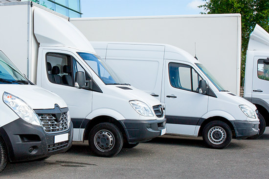  Several white vans lined up in front of a building, illustrating fleet insurance options for Laredo transportation firms.