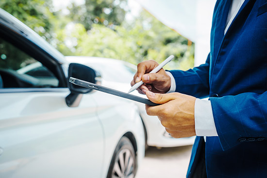 A suited man holds a pen and writes on a tablet, sharing insights on car insurance in Laredo, TX.