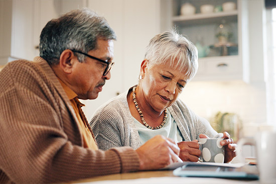 An elderly couple sits at a table, looking at a tablet, exploring independent insurance options for RGV homeowners in 2026.