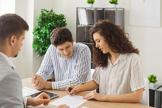 Three people at a table engaged in signing documents about liability insurance tips for small businesses in McAllen.