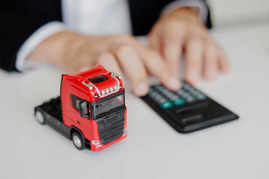 Businessman working in office with calculator. Calculation of logistics costs. Toy cargo truck on the table.