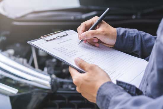 Revisión de coches, concepto de taller de mantenimiento de vehículos. Un mecánico de coches escribiendo una lista de tareas en un portapapeles, un mecánico revisando el motor para calcular el coste de la reparación, un ingeniero inspeccionando el mantenimiento en un taller de coches